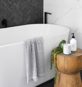 A bathroom with a tub, stool and plants.