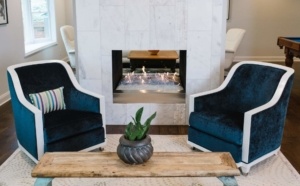 A living room with two blue chairs and a fireplace.