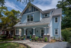 A blue house with a porch and lots of windows.