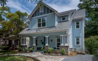 A blue house with a porch and lots of windows.