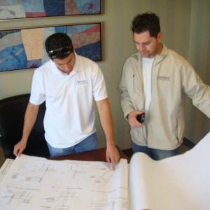 Two men looking at a plan on top of a table.