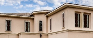 A large beige house with two windows and a door.
