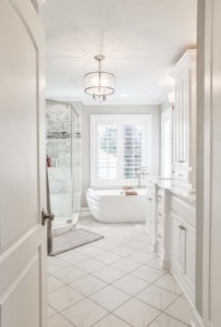 A bathroom with white tile and a large glass shower.