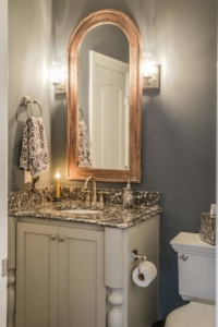 A bathroom with a sink, mirror and towel rack.