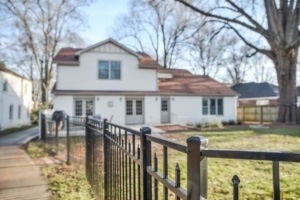 A house with a fence and a horse in the yard.