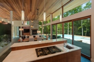 A kitchen with a large window and wooden ceiling.