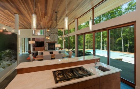 A kitchen with a large window and wooden ceiling.