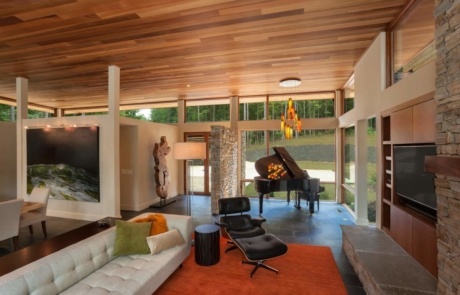 A living room with a couch, chair and piano.