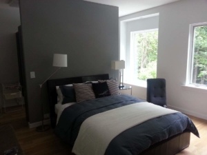 A bedroom with a bed, nightstand and window.