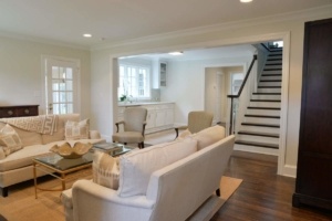 A living room with stairs and white furniture.