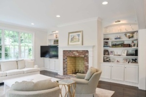 A living room with white furniture and a fireplace.