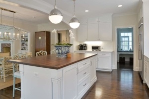 A kitchen with white cabinets and wood countertops.