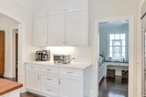 A kitchen with white cabinets and wood floors.