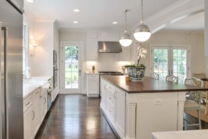 A kitchen with white cabinets and wood floors.