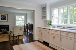 A kitchen with white cabinets and wooden floors.