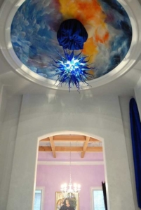 A ceiling with a blue glass chandelier hanging from the middle of it.