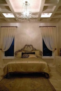 A bedroom with two windows and a bed