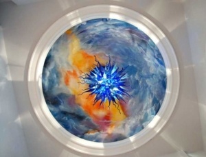 A circular painting of an abstract scene with blue and orange colors.