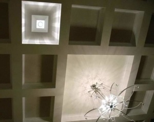 A chandelier in the center of a room with white walls.