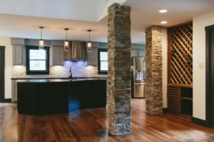 A kitchen with a stone pillar and wooden floor