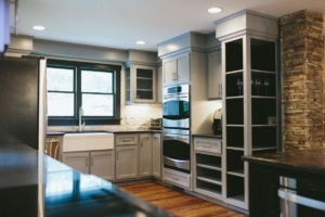 A kitchen with gray cabinets and black counter tops.