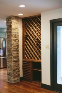 A wine cellar with a stone wall and wooden shelves.