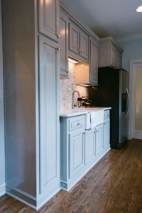 A kitchen with white cabinets and black appliances.