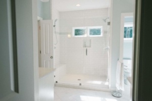 A white bathroom with a walk in shower and tiled floor.
