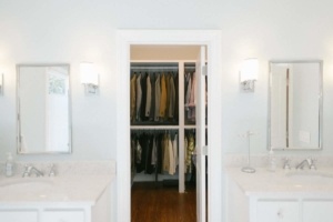 A bathroom with two sinks and a walk in closet.