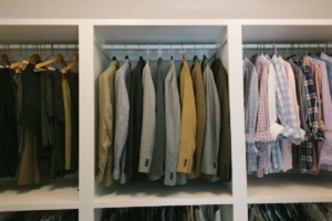 A closet with several different colored shirts hanging.