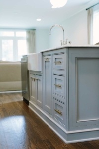 A kitchen with white cabinets and wood floors.