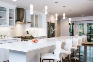 A kitchen with white counters and white stools.