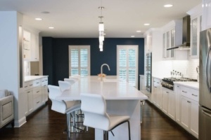 A kitchen with white cabinets and dark wood floors.