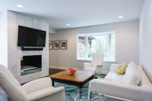 A living room with white furniture and a fireplace.