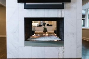 A fireplace with a television above it and a fire in the middle.