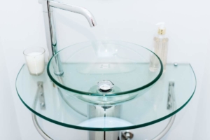 A glass sink with two bowls and a faucet.