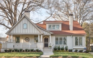 A white house with a red roof and a porch.