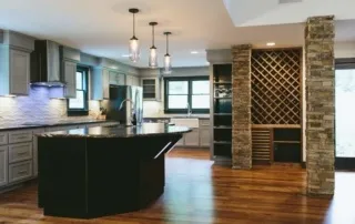 A kitchen with wooden floors and black cabinets.