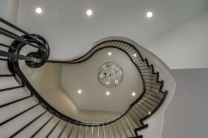 A spiral staircase with lights and a clock on the wall.