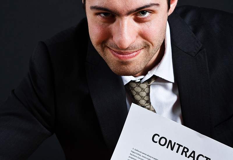 A man in suit and tie holding up a contract.