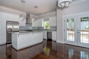 A kitchen with white cabinets and wood floors.