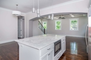 A kitchen with white cabinets and marble counter tops.
