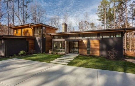 A modern house with grass and trees in the background.