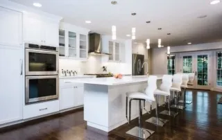 A kitchen with white cabinets and wooden floors.