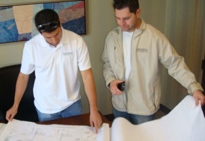 Two men looking at a plan on top of a table.