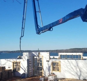 A crane is lifting the roof of a house.