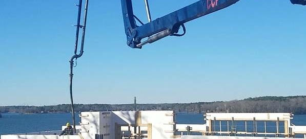 A crane is lifting the roof of a house.