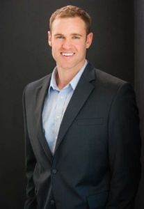 A man in a suit and tie smiling for the camera.