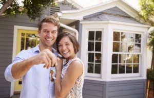 A man and woman holding keys to their new home.