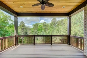 A porch with a ceiling fan and wooden railing.